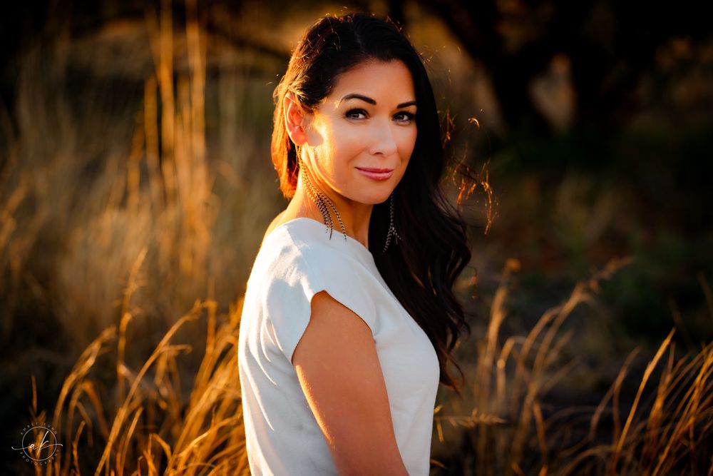 Golden hour portrait shows woman in white top against backdrop of sun-kissed Sedona grass.