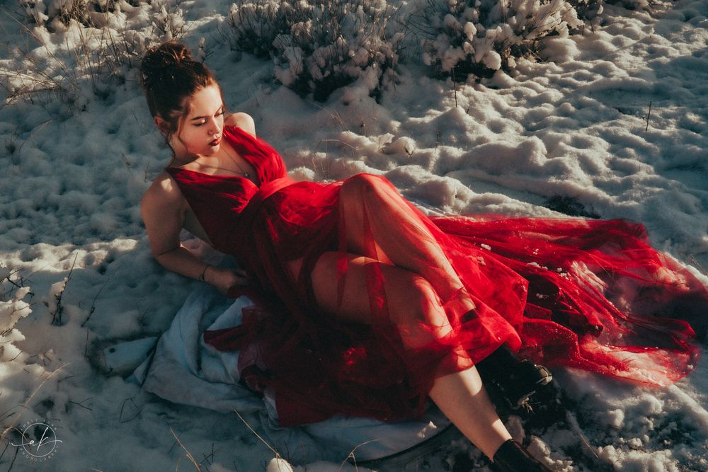 Romantic beach scene with flowing red dress on white sand.