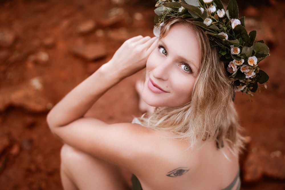 Ethereal portrait with floral crown against Sedona red earth background in natural light.