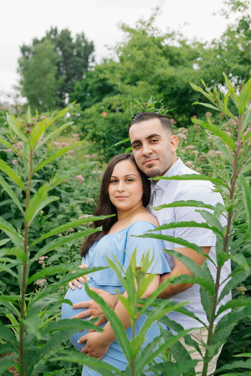 a couple embrace each other during their maternity session in Roosevelt Island by Paula Ortiz NYC family photographer