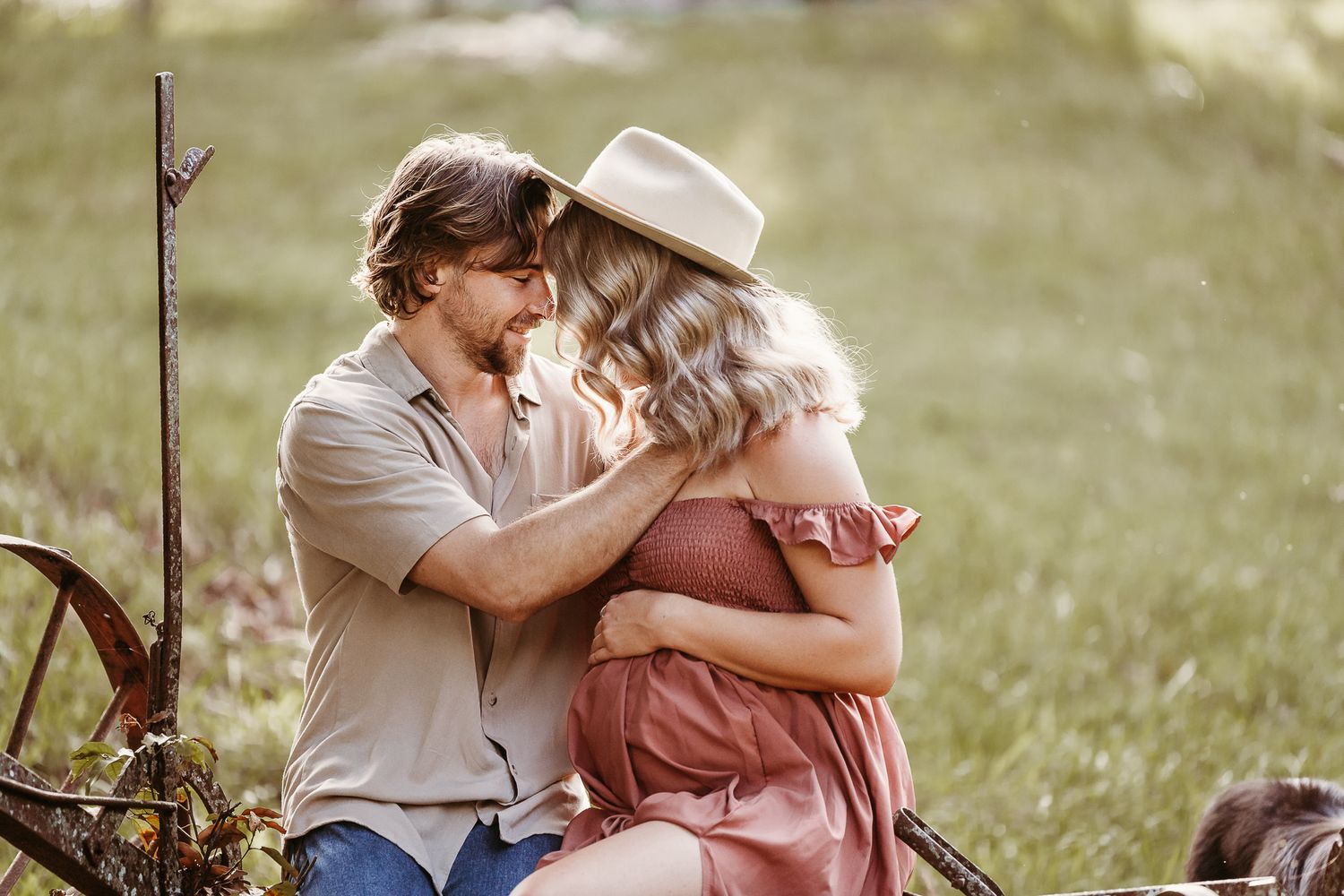 A tender embrace in golden sunlight with vintage-inspired clothing in a meadow setting.