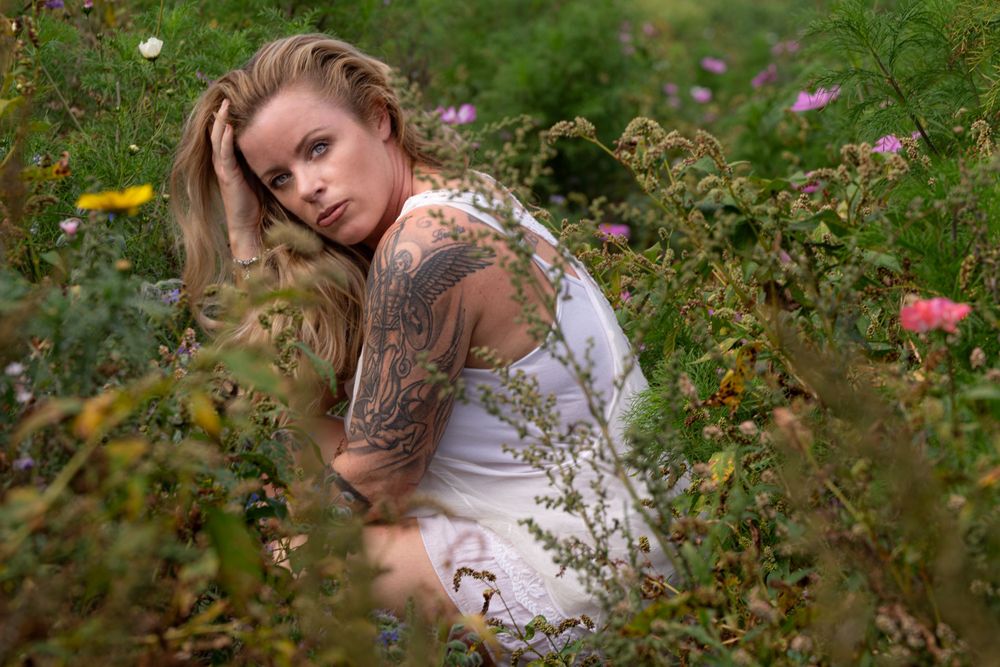 Artistic outdoor portrait among wildflowers and natural garden growth.
