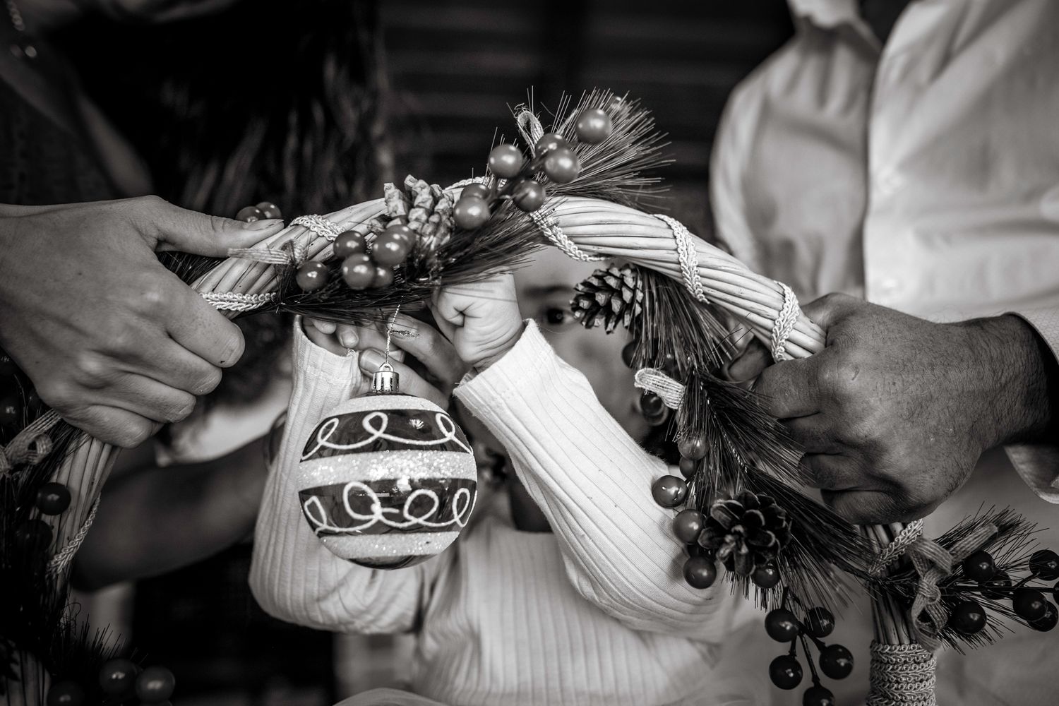 Black and white photo of a girl hanging a Christmas ball on a basket