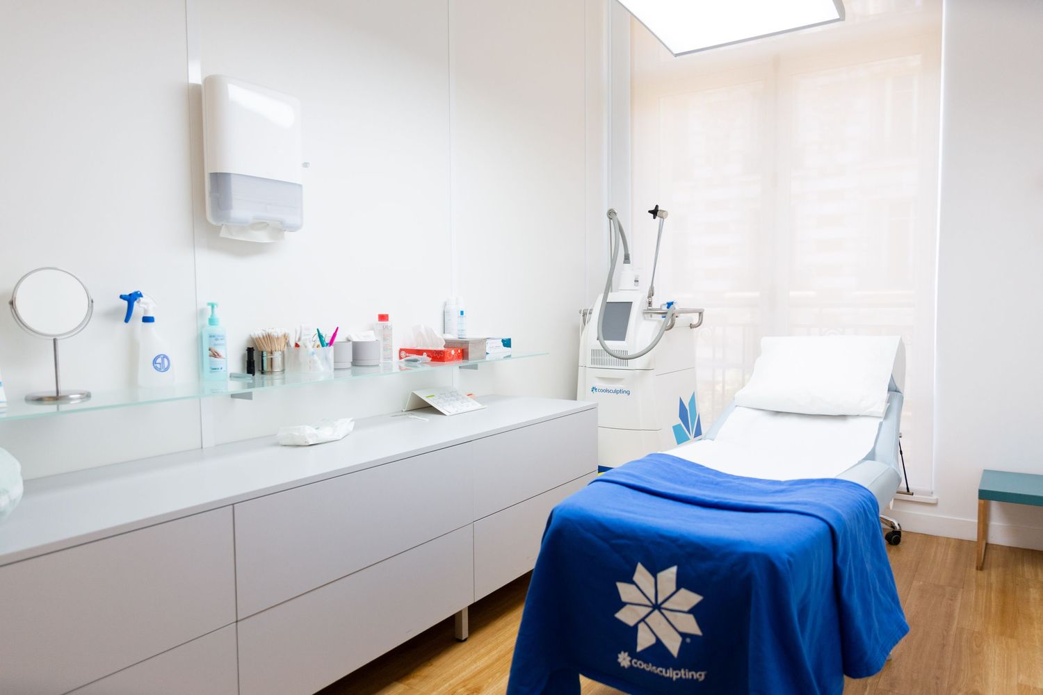 Clean modern medical treatment room with white cabinets and blue treatment bed.