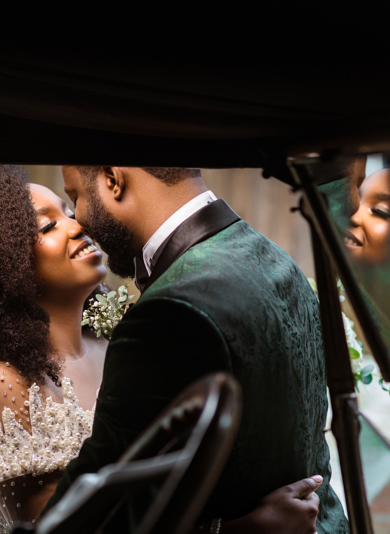 Intimate wedding couple sharing a tender moment in a dark green velvet suit and beaded dress.