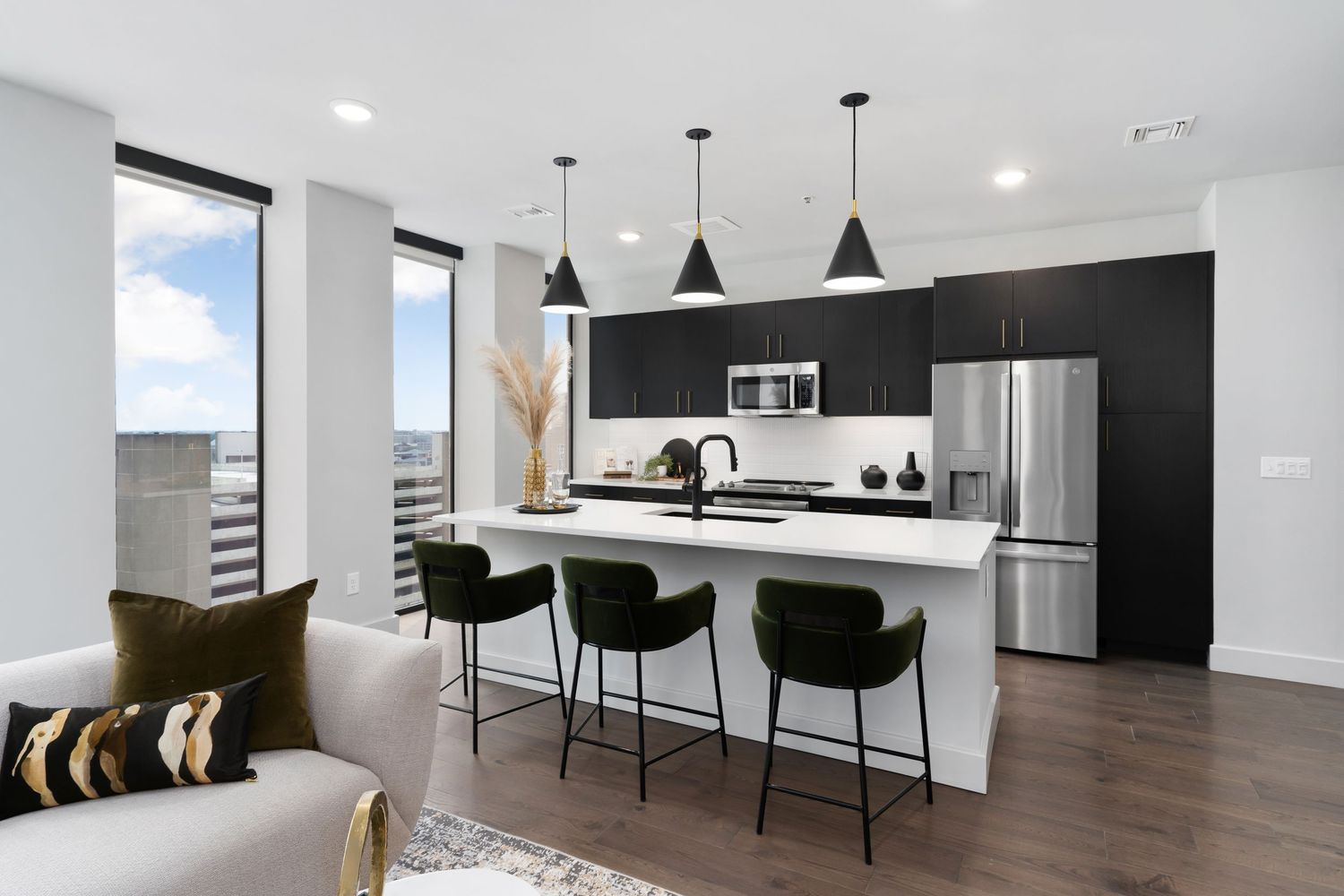 Downtown Columbus Ohio kitchen with white island, black cabinets, stainless appliances and pendant lights in a luxury apartment.