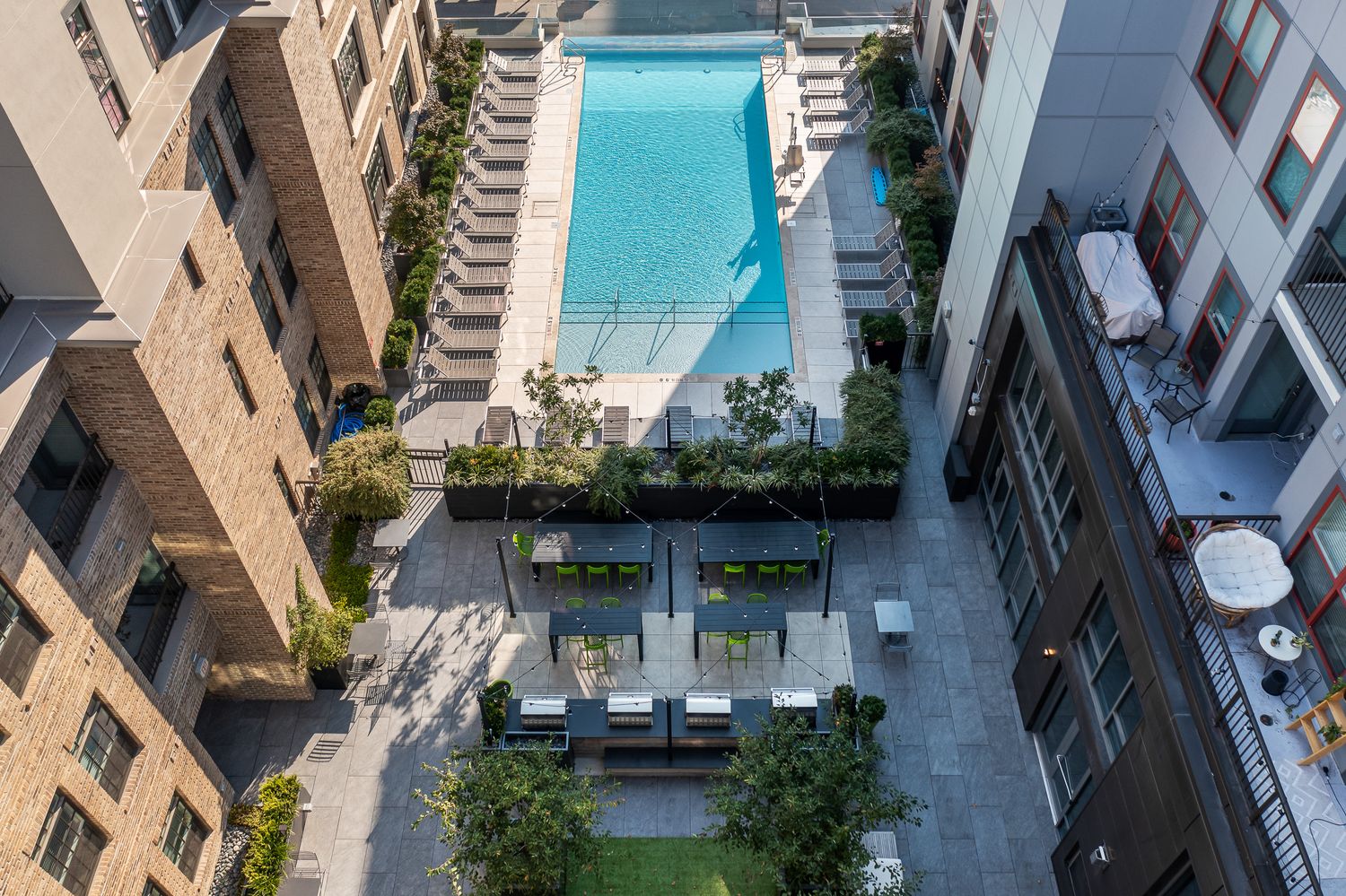 Aerial view of a modern apartment complex courtyard featuring a swimming pool, lounge chairs, and outdoor seating area in Columbus Ohio.