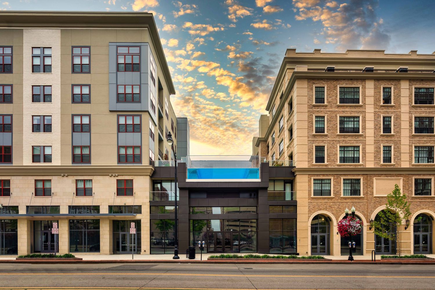Modern mixed-use apartment buildings with retail spaces on ground level against a dramatic sunset sky in Columbus, Ohio