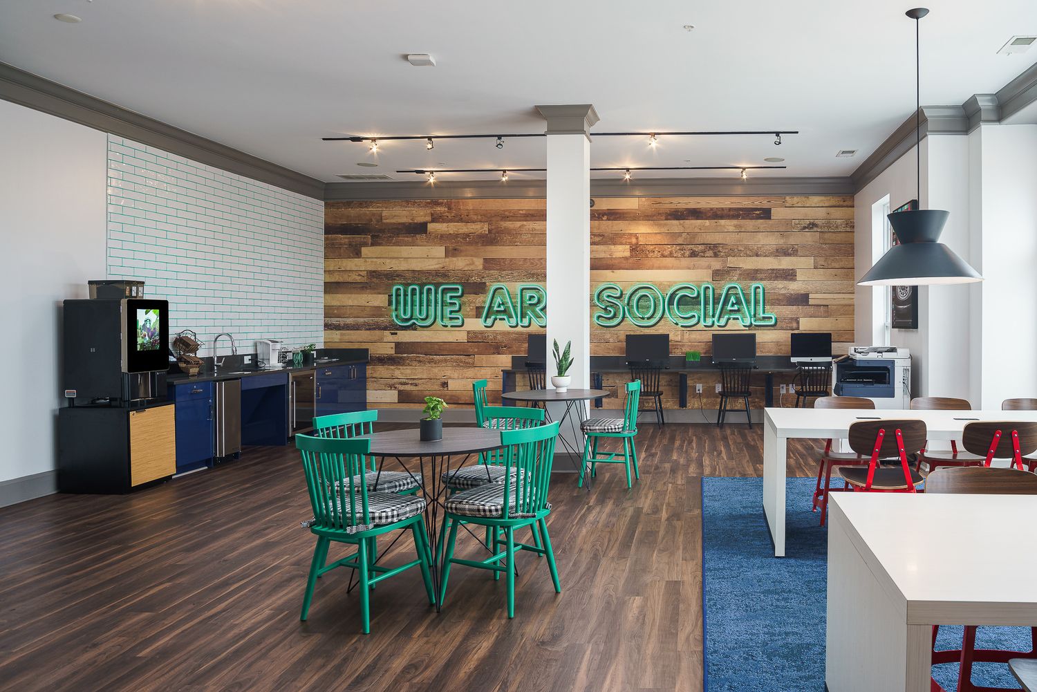 Modern college apartment study room with reclaimed wood walls, green chairs, and track lighting with a sleek industrial design aesthetic.