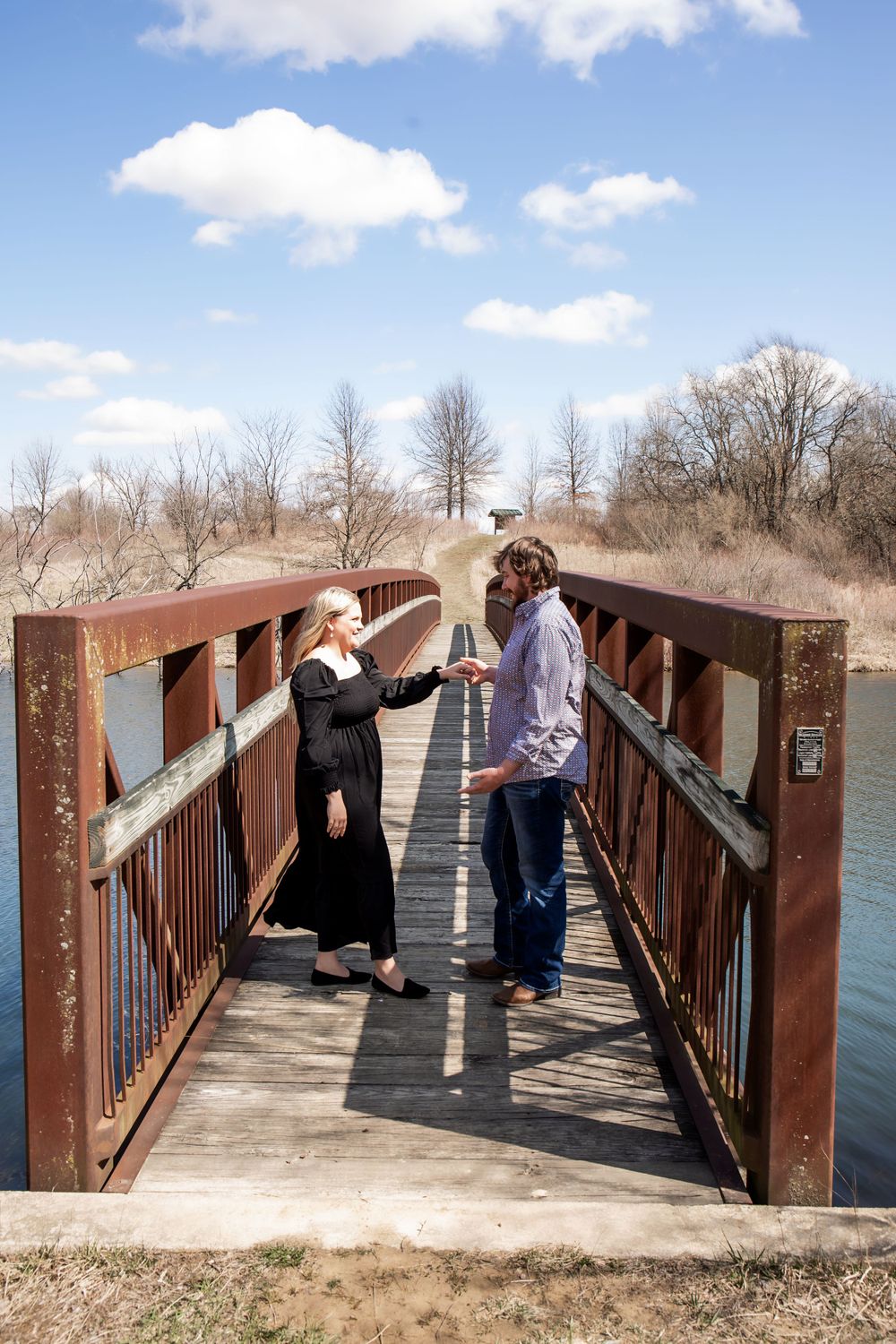 A couple dancing and twirling together on a rustic wooden bridge over water.