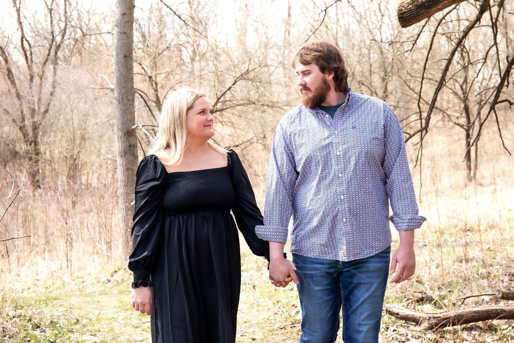 Couple walking hand in hand through a winter forest landscape.