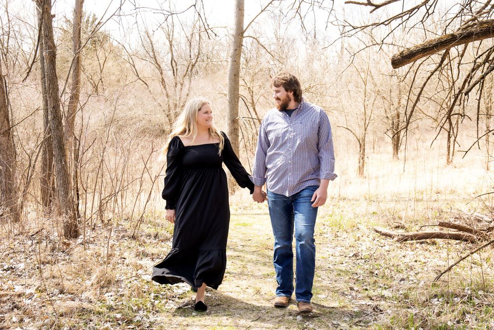 Couple taking a romantic stroll through bare trees in natural lighting.
