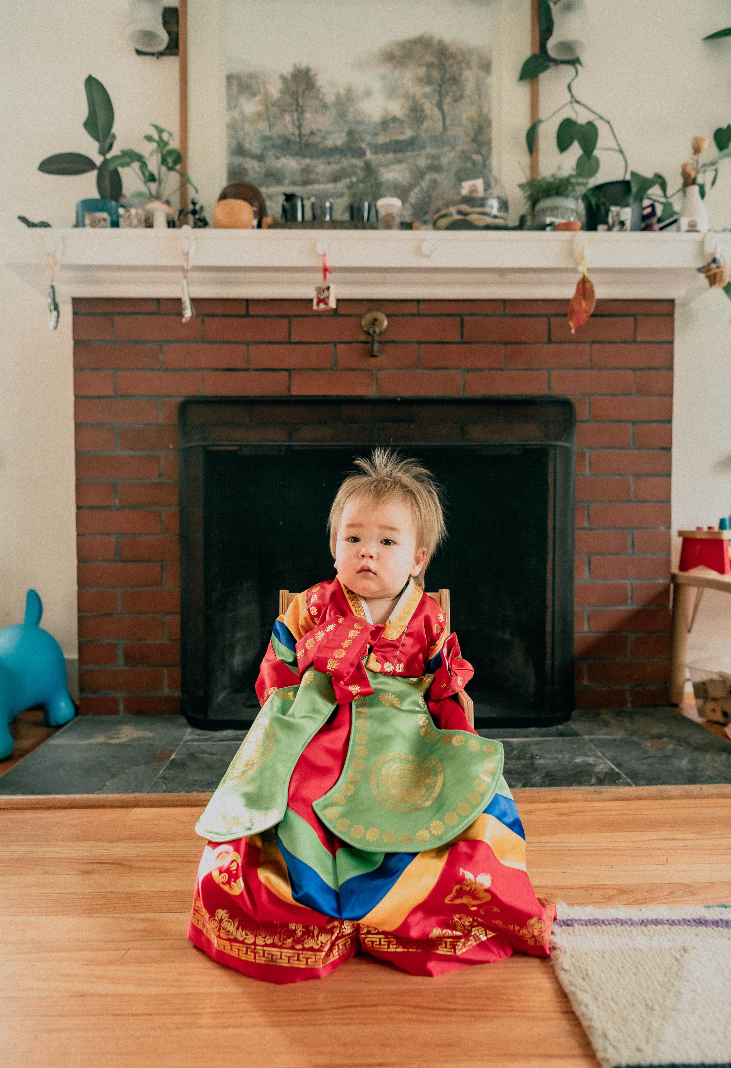 Adorable baby in traditional Korean outfit posed in front of the fireplace.