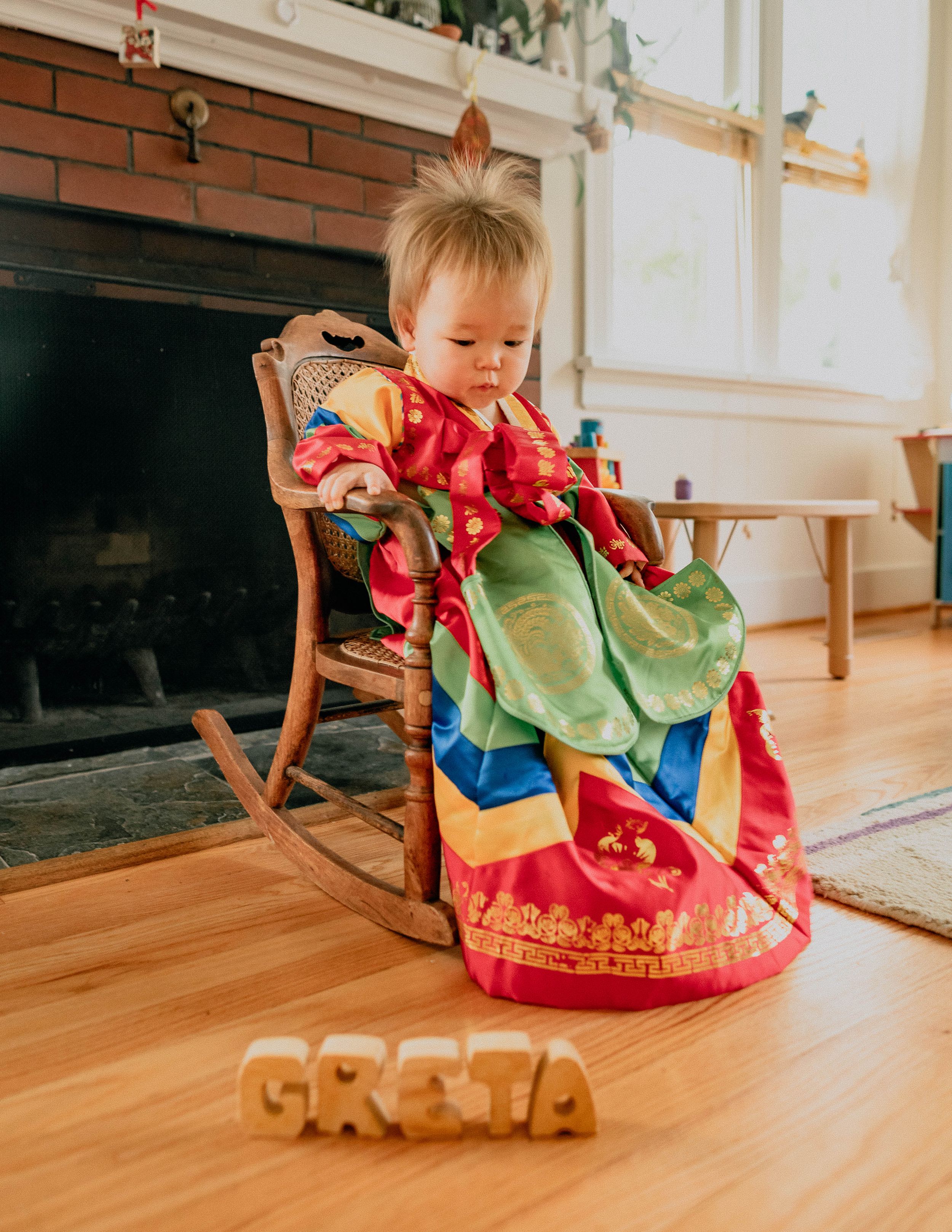 Adorable baby in traditional Korean outfit posed in front of the fireplace.