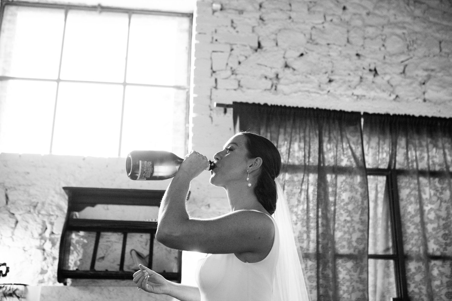 A bride takes a swig out of. bottle of Prosecco before her Tuscan wedding.