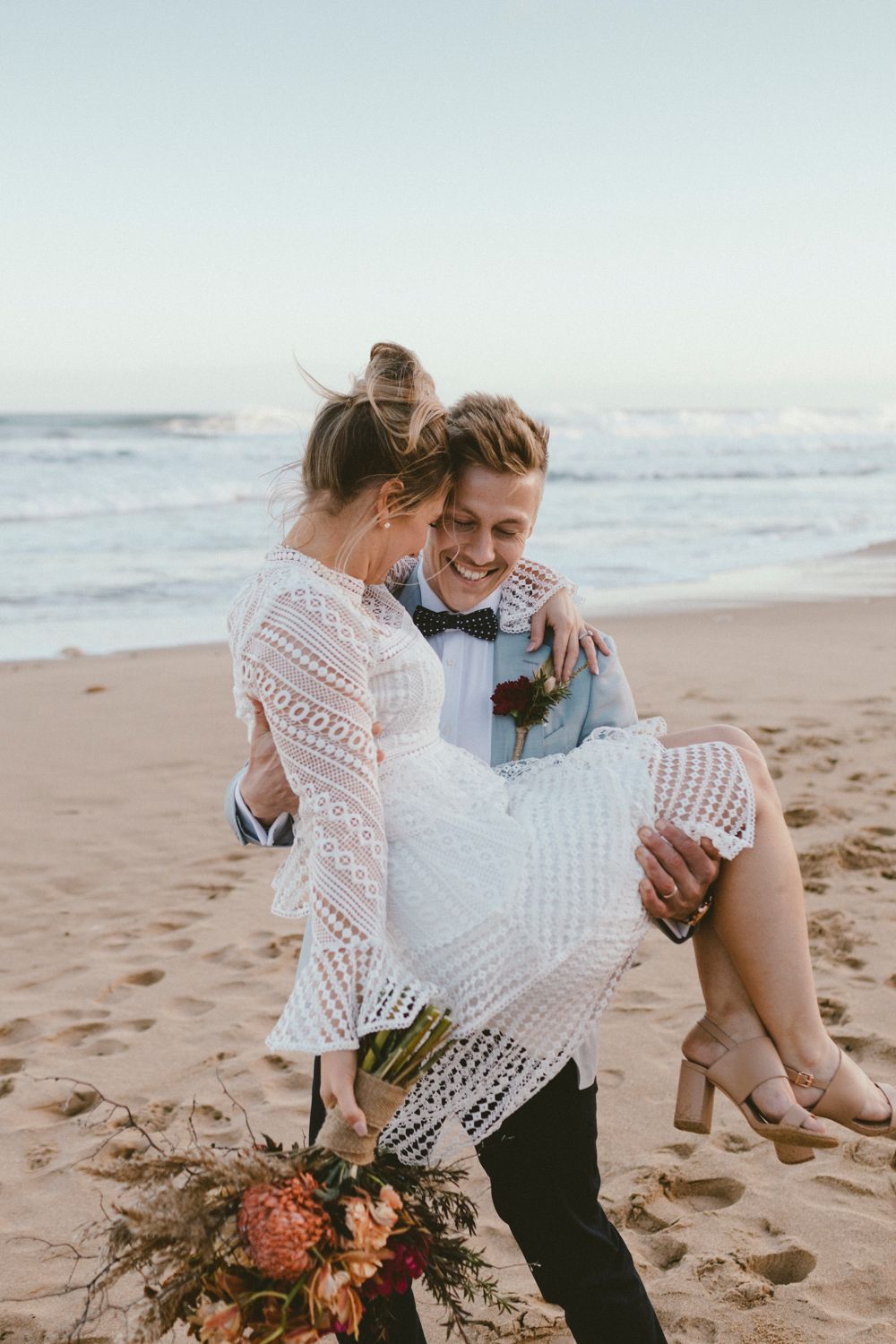 Romantic moment shared on a sandy beach with crashing waves in the background.
