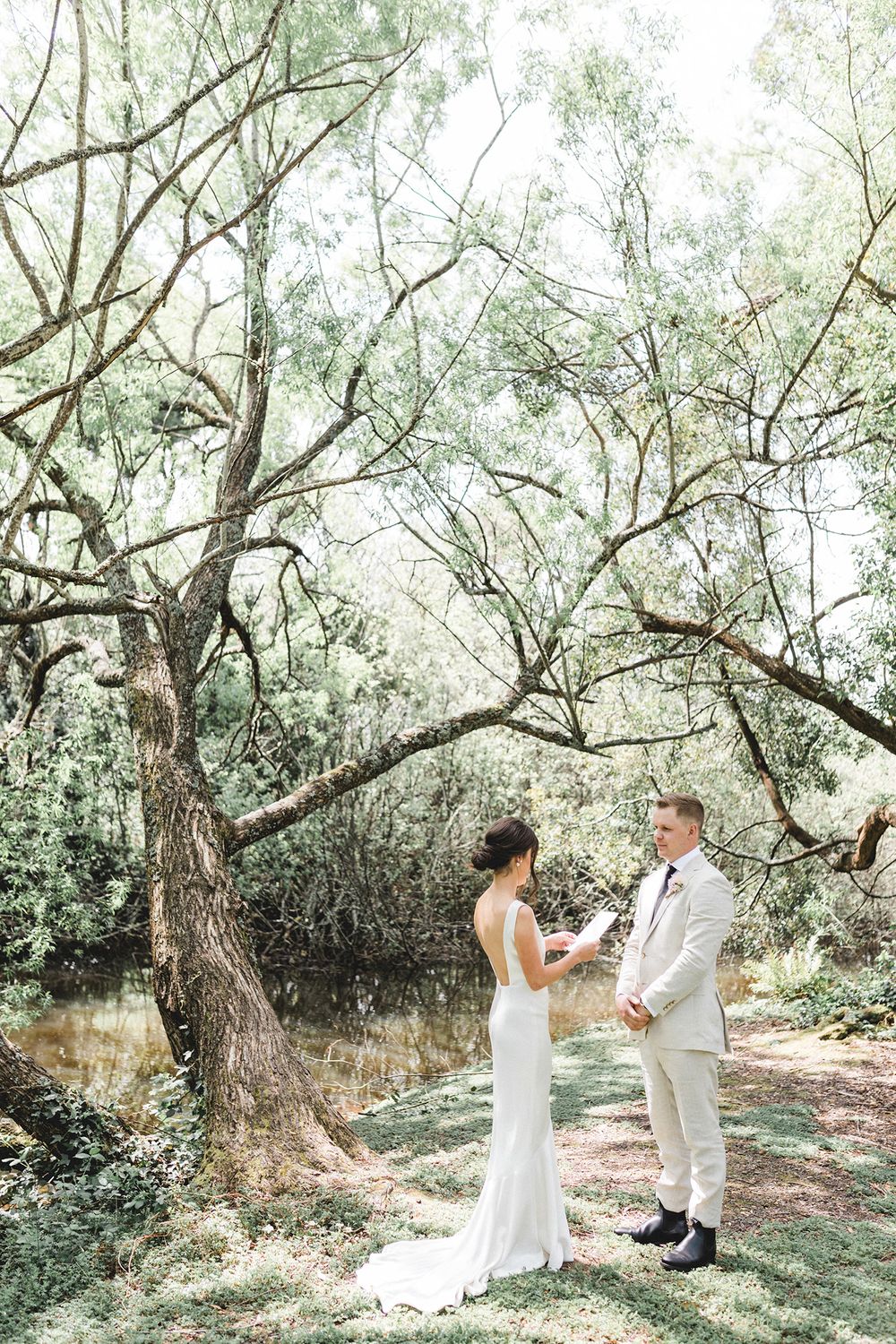 Wedding ceremony in a serene woodland setting with natural light filtering through trees.
