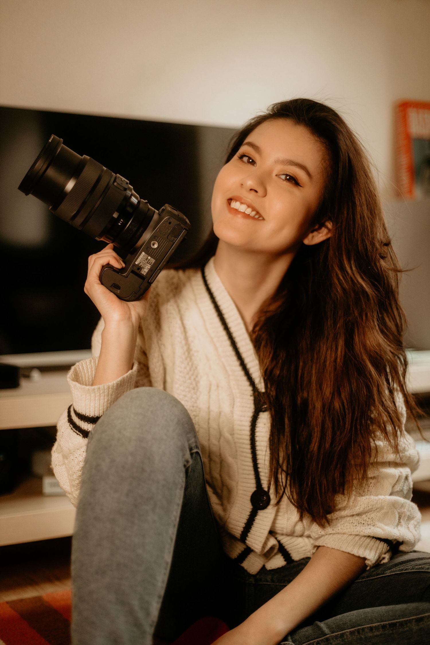 Celala, photographe mariage Clermont-Ferrand Auvergne Rhône-Alpes, en portrait complice avec appareil photo vintage et pull crème.
