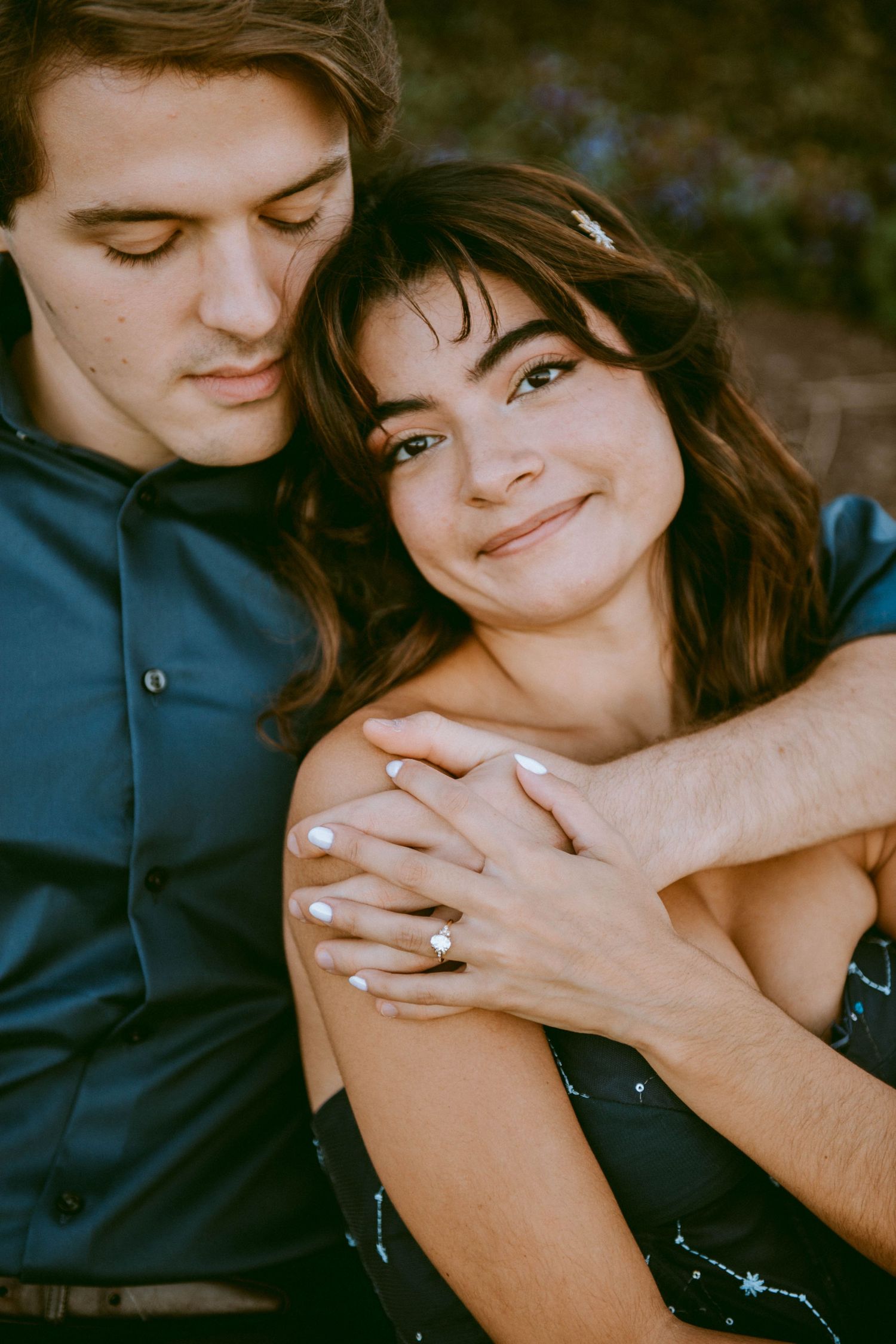 girl resting in her finance's embrace with his arms wrapped around her