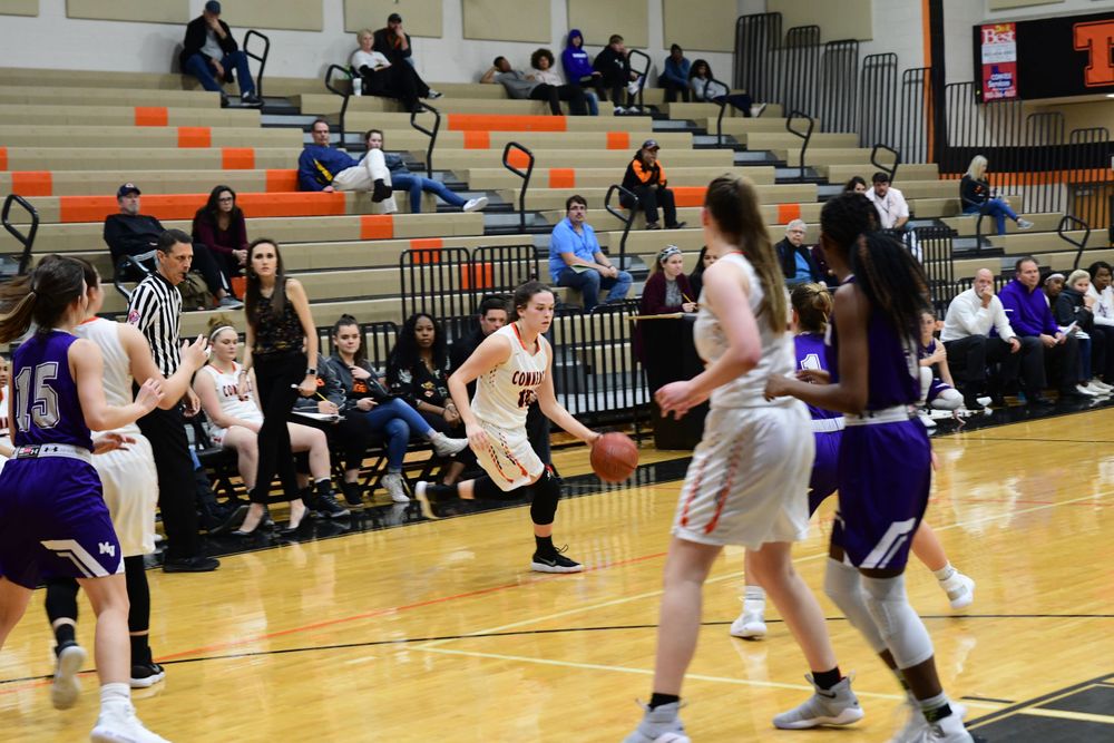 High school basketball players compete in a gymnasium during an intense game action moment.