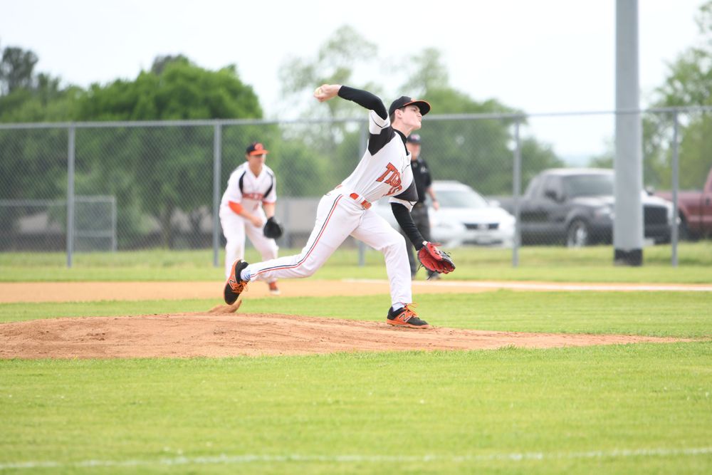 Baseball pitcher in mid-throw motion on pitching mound during game action.