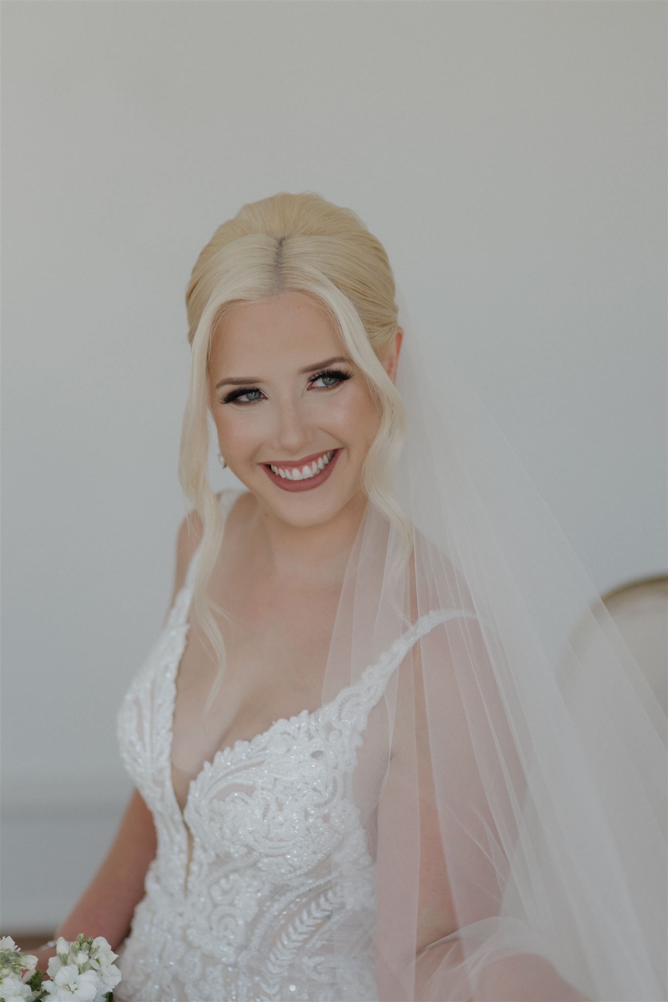 Close up portrait of a bride wearing a plunging v-neck lace gown and flowing veil on her wedding day.