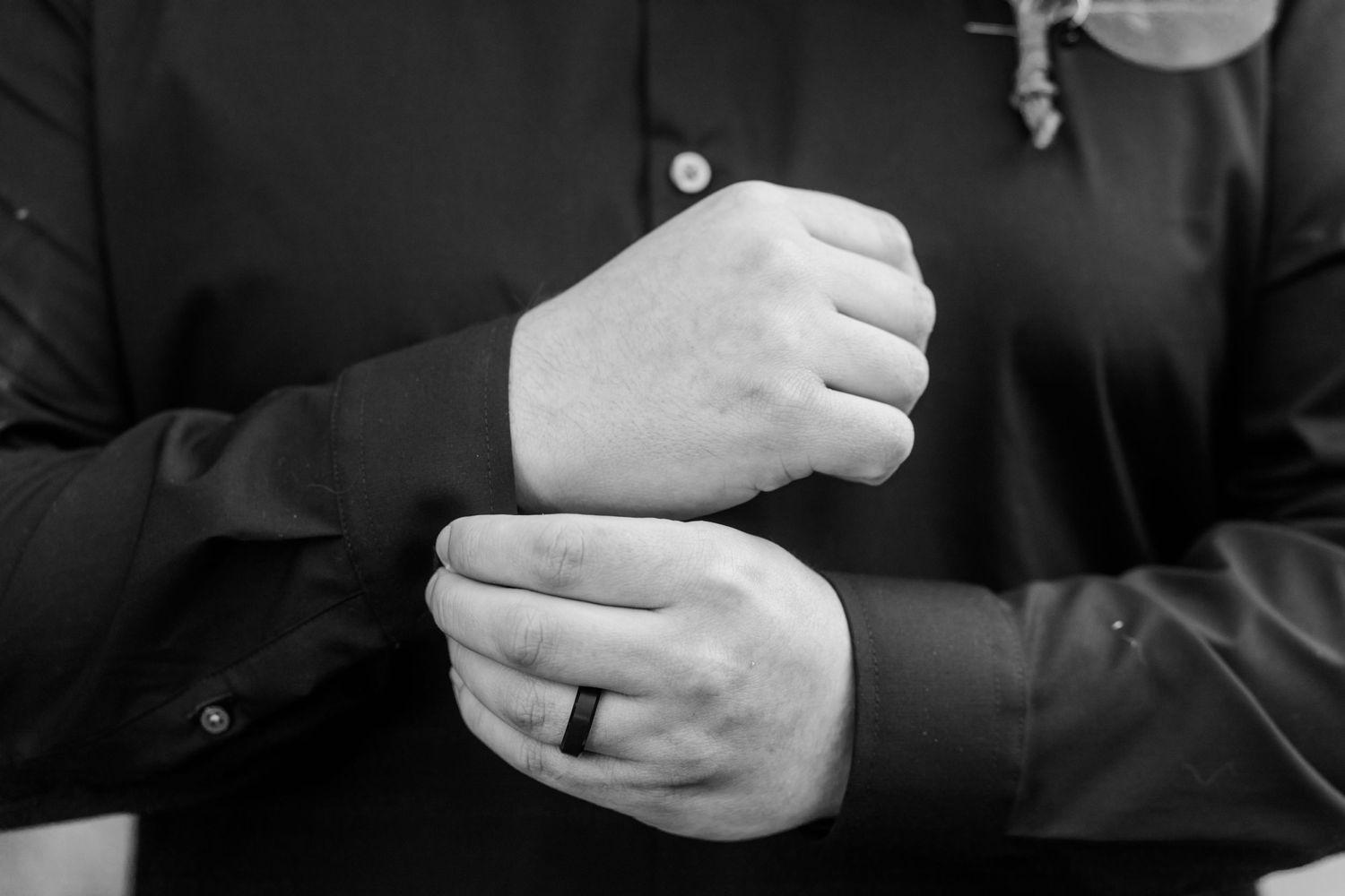 Black and white detail shot of hands during wedding ceremony.