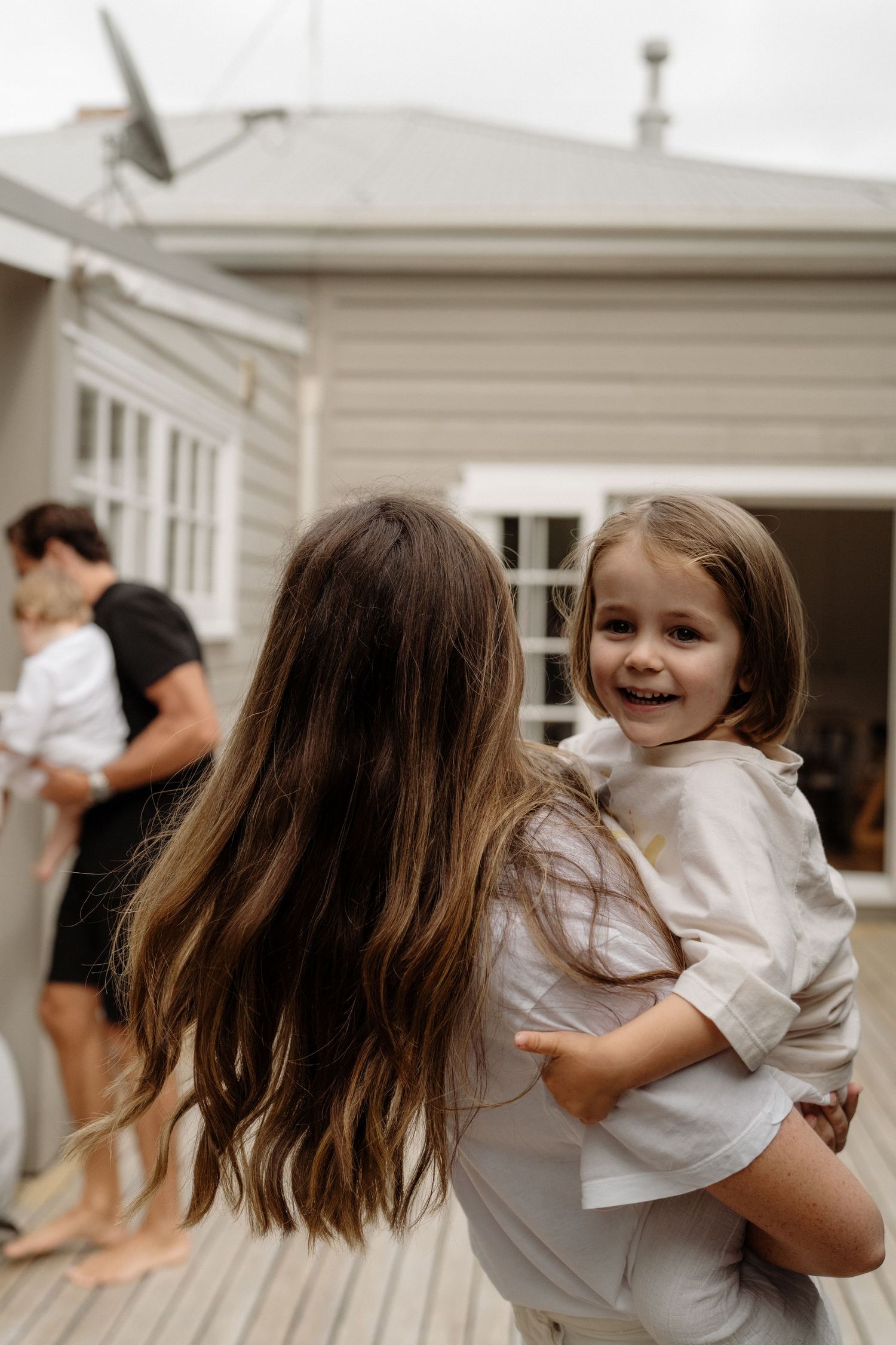Mum giving son a piggyback on deck.  Family fun candid photography Auckland Greenlane