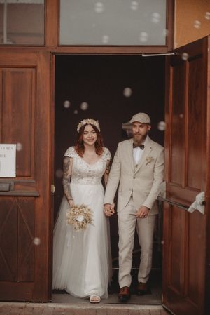 Newlyweds exiting wooden doors with bubbles floating in the air.