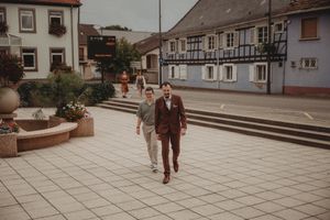 Well-dressed individual walks across a European town square with historic buildings in background.