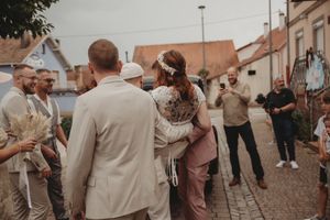 Wedding guests gather on a cobblestone street in neutral-colored attire.