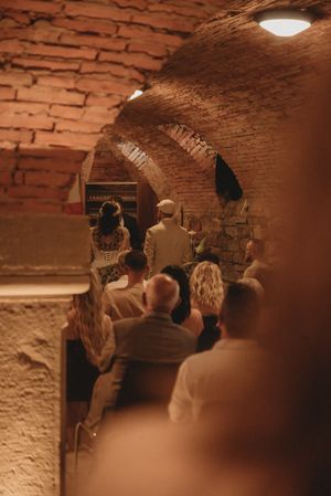 Guests gathered in a historic brick cellar during a wedding ceremony.