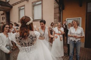 Wedding celebration with guests gathered outside as the bride stands in a corset-back dress.