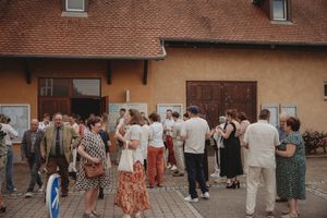 Crowd of wedding guests mingling outside a peach-colored building.