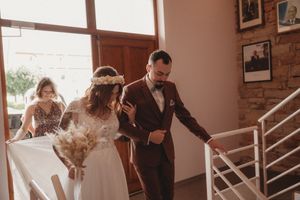 A wedding couple descending stairs in an indoor venue with peach-colored walls.