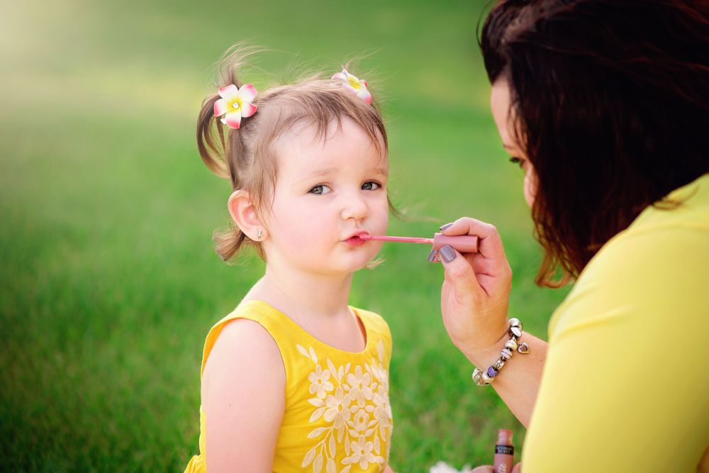 Mom applies lip gloss to daughter's lips during a mommy and me session in Kingwood, TX