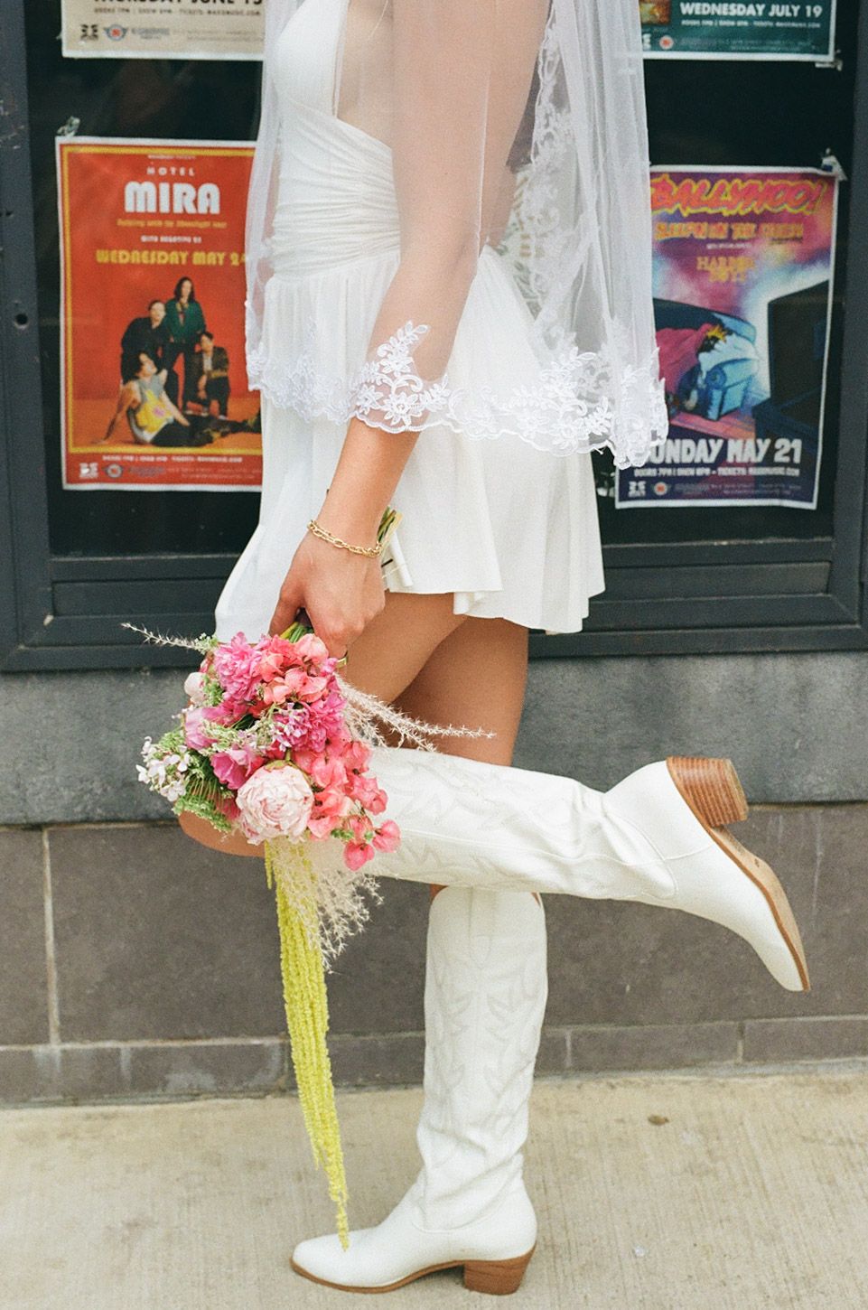 White boots and floral bouquet detail against movie posters on wall.
