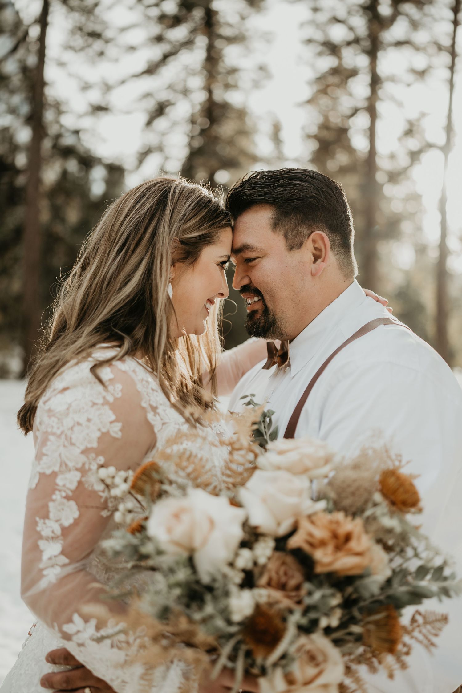 Intimate wedding portrait with couple sharing tender moment and holding floral bouquet.