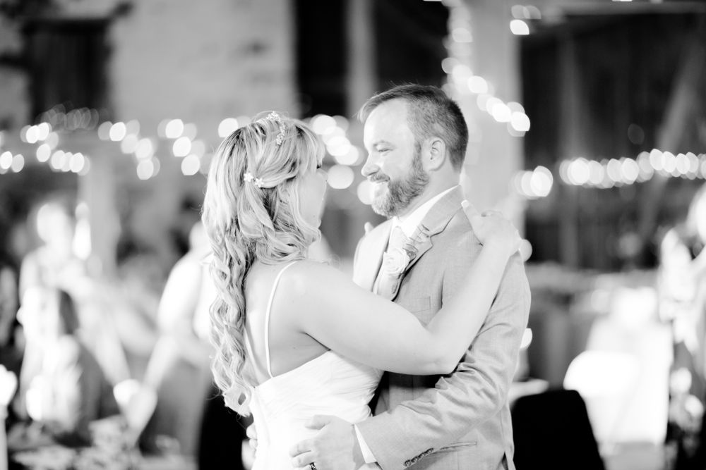 A black and white capture of a couple sharing a joyful dance moment at their wedding.