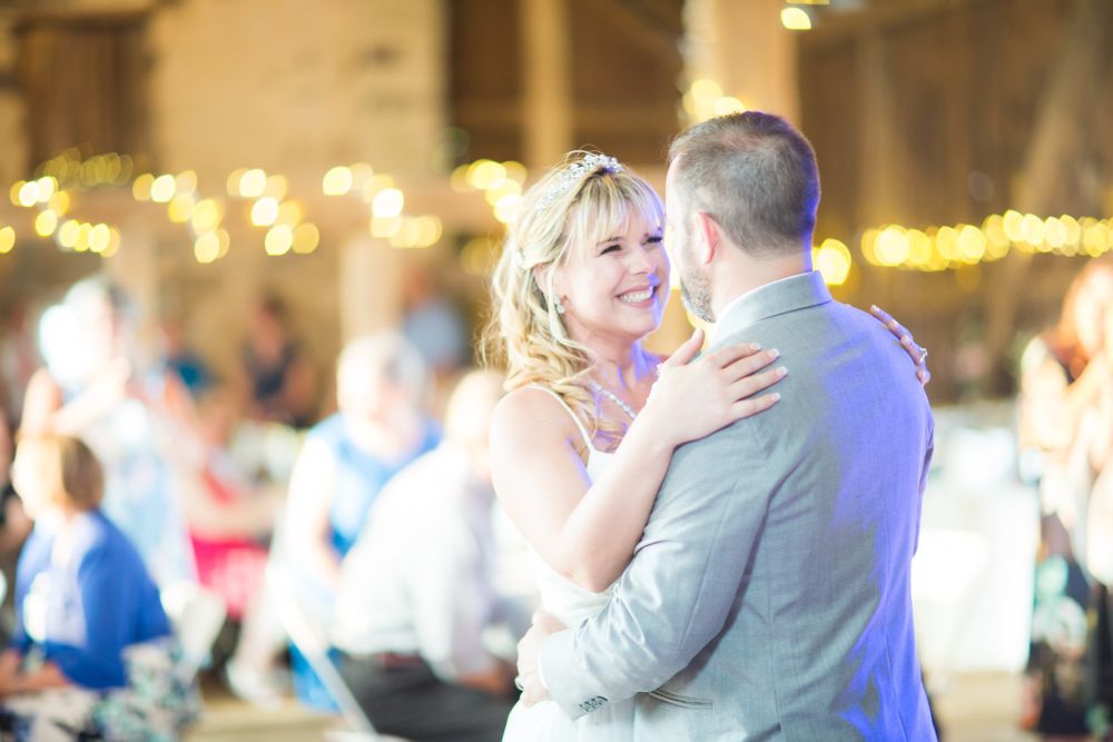A couple shares a romantic dance moment surrounded by twinkling lights at their wedding reception.