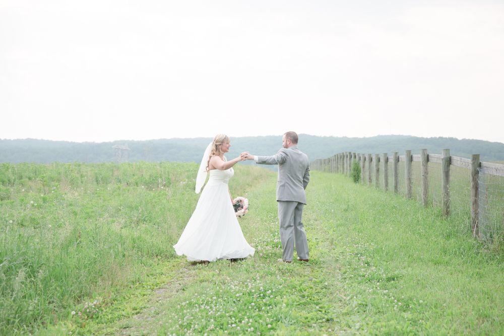 A couple dances together on a rustic country path lined with wooden fence posts.