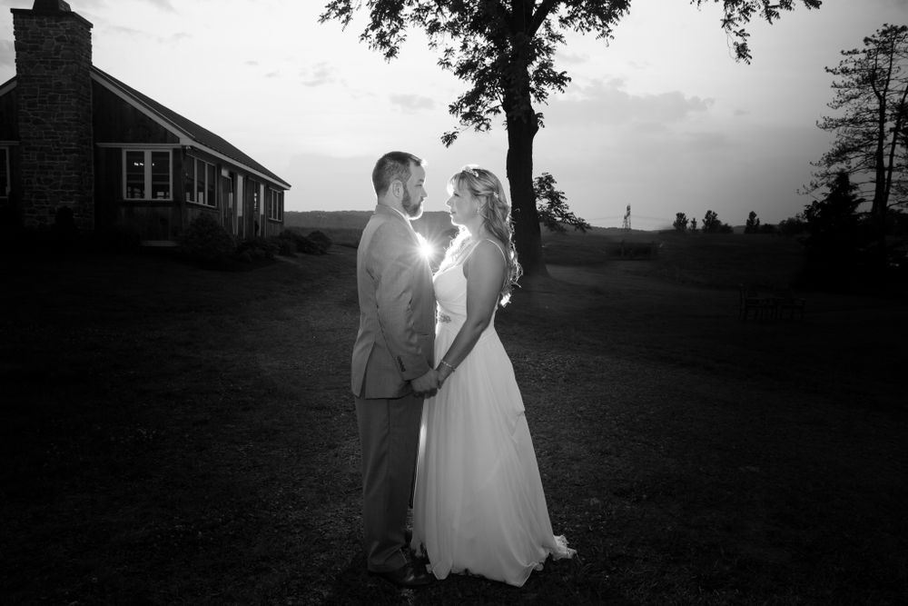 A romantic outdoor silhouette shot of a couple on their wedding day at sunset with a house in the background.