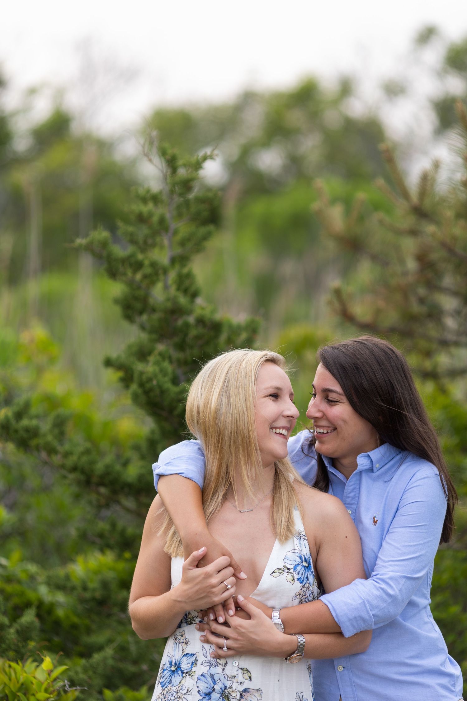 A couple shares a tender moment together while embracing in a garden setting with green foliage in the background.