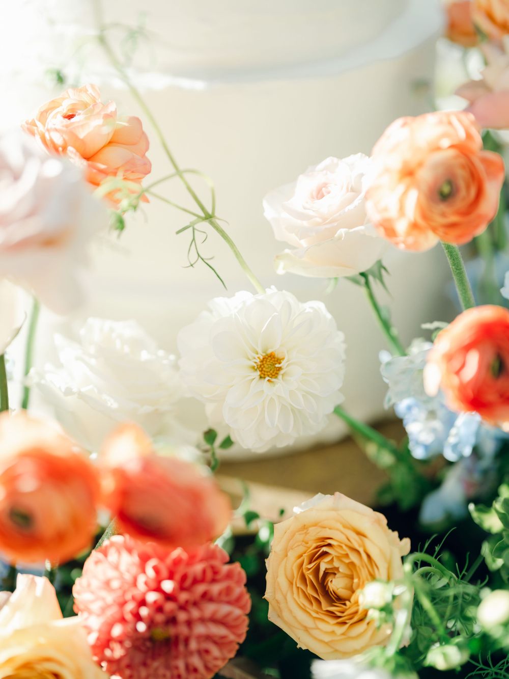 Close-up of romantic garden roses and dahlias in peach, coral, and white tones.