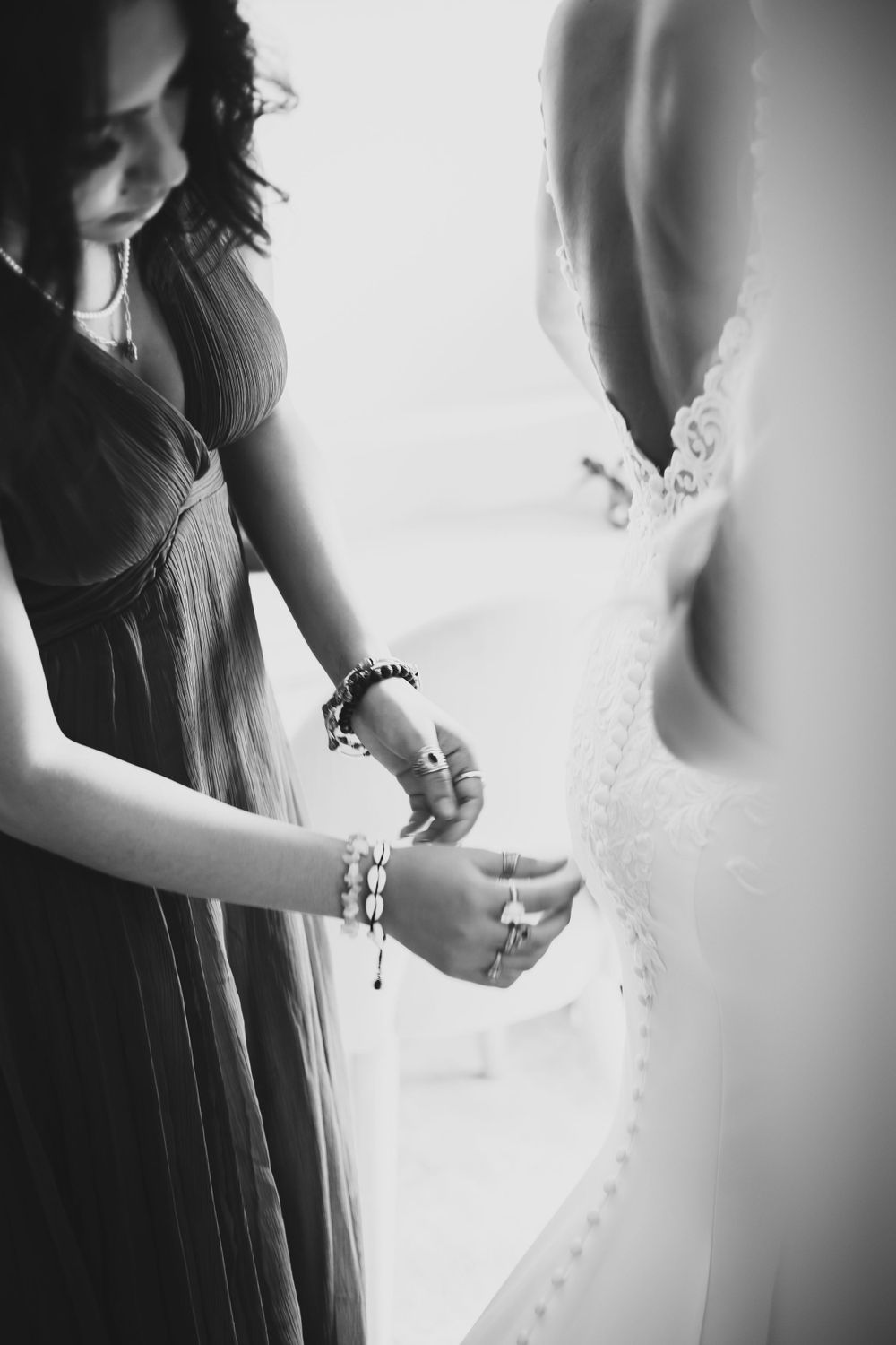 bridemaid helping bride into dress