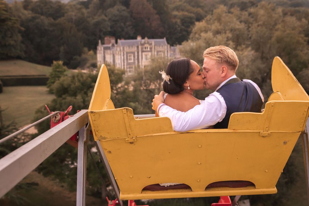 bride and groom kissing on a carousel with manor house in the background