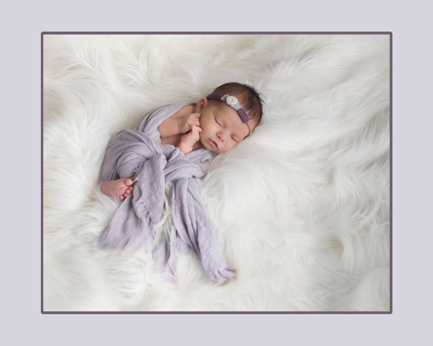 A peaceful newborn sleeps on soft white fur, wrapped in delicate lavender fabric.