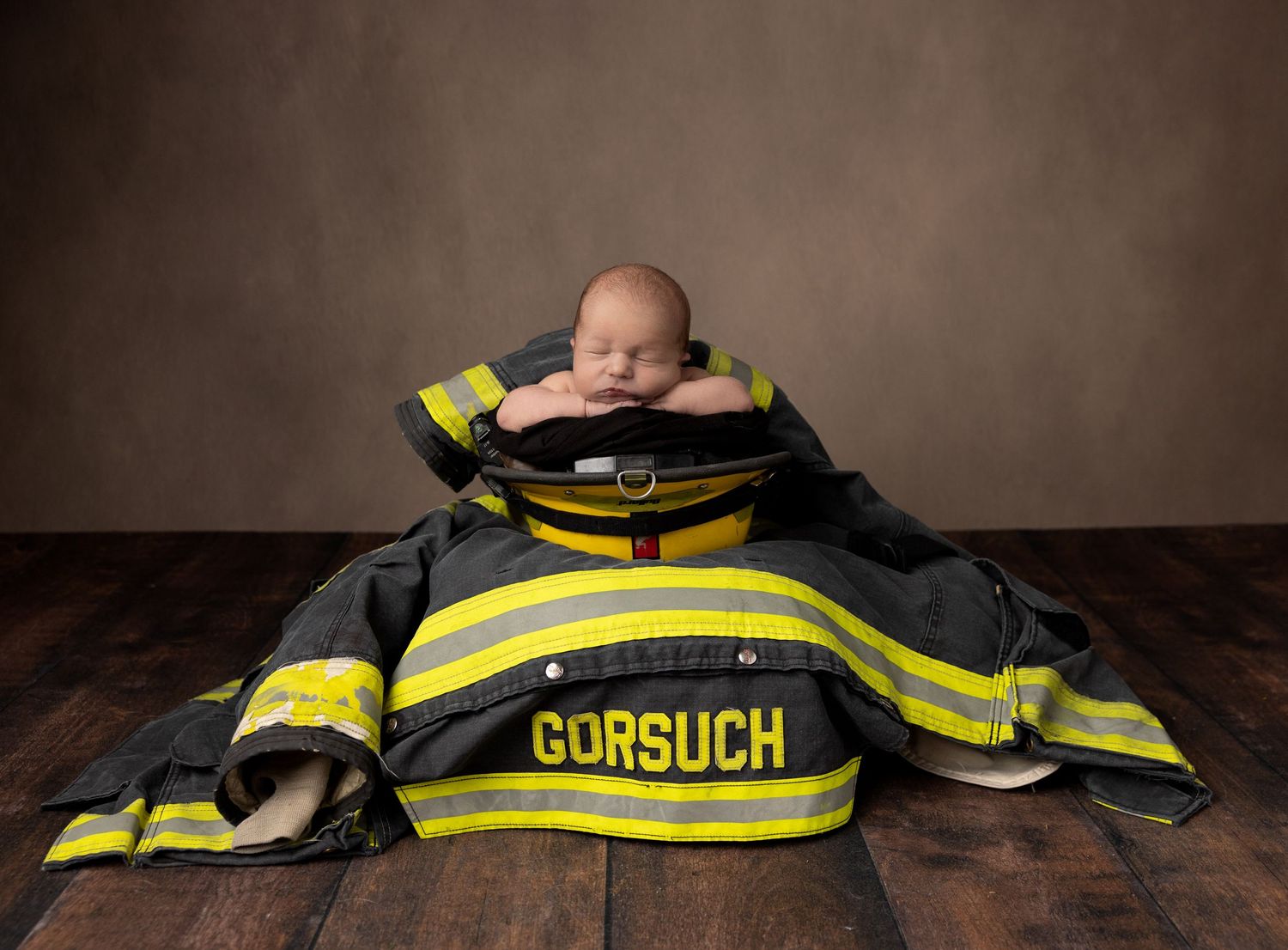 Yellow firefighter uniform jacket laid out flat on wooden surface.