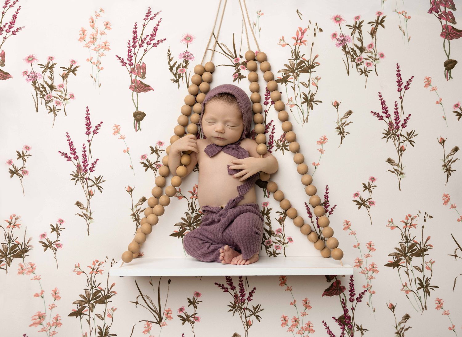 A series of artistic baby photography portraits against a vintage floral backdrop.