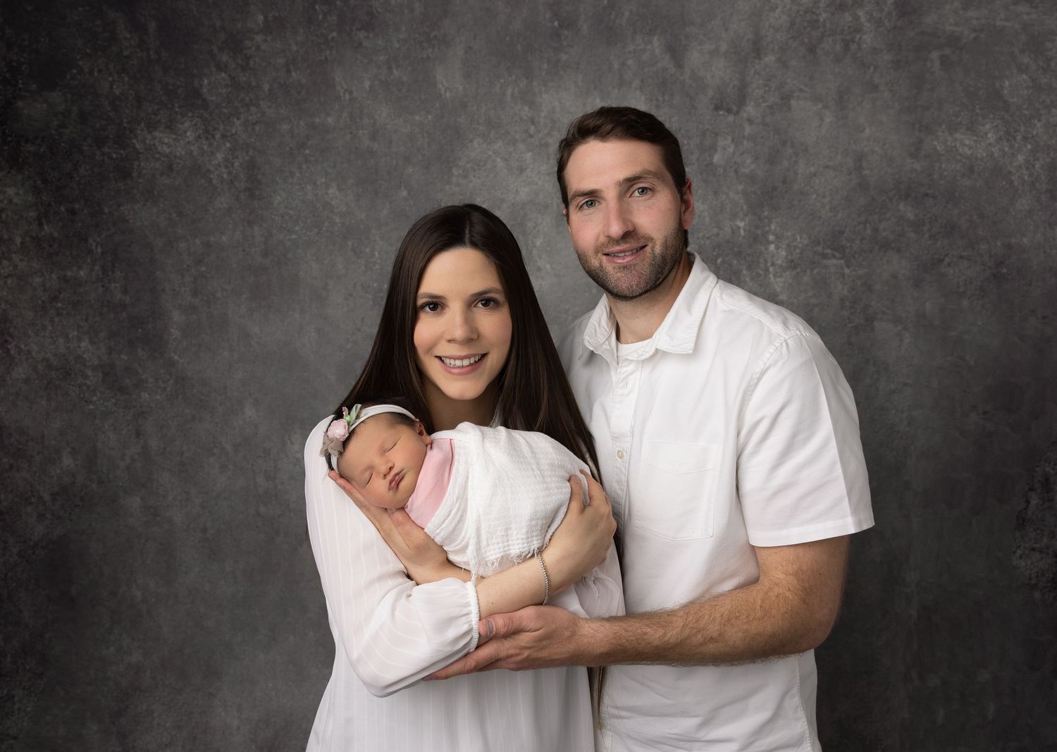 Family portrait series against grey backdrop wearing coordinated white outfits.